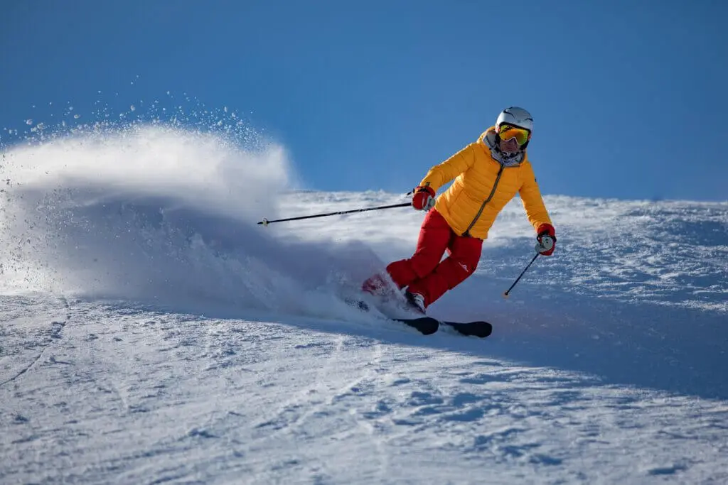 Skieur qui descend la pente belle neige beau temps chaussures de ski confortables